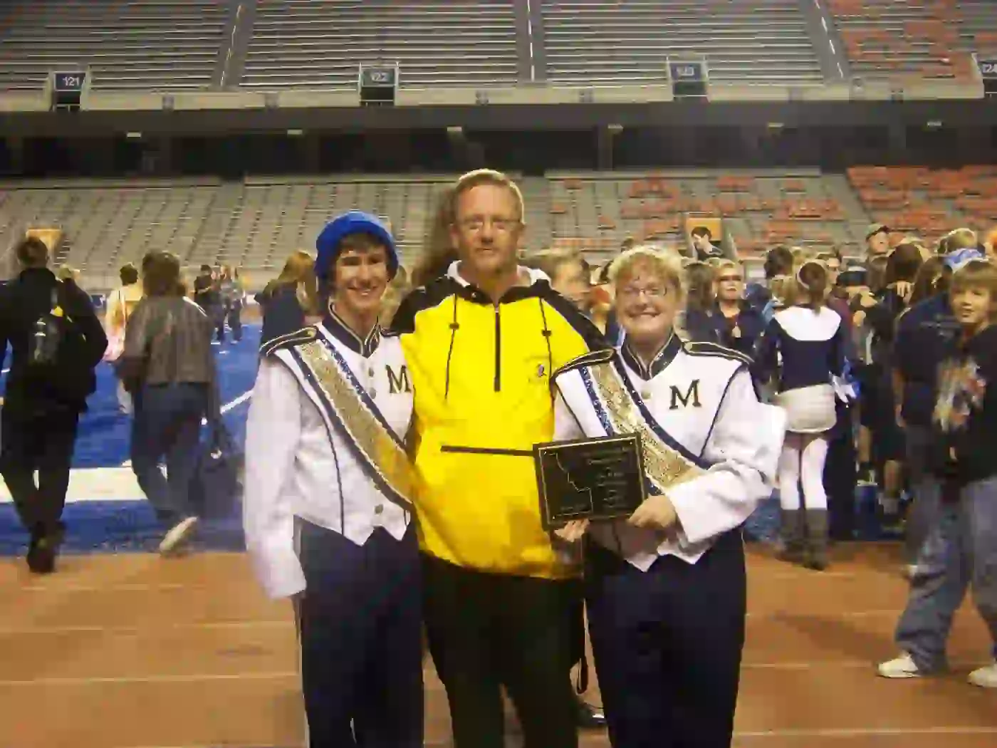Sam Bowker with Meridian drumline students holding an award plaque on the track