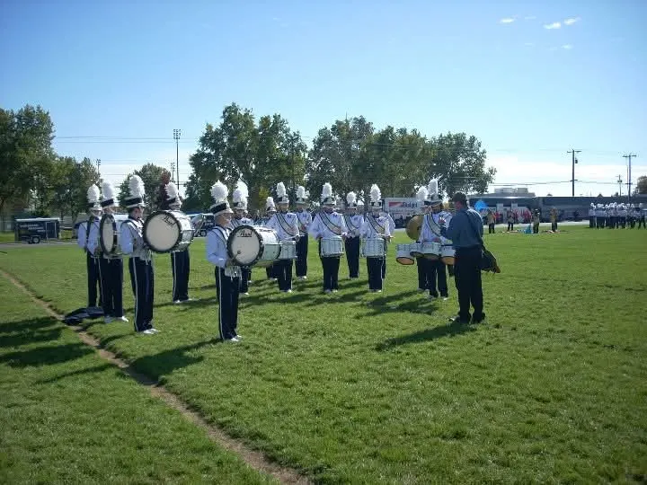 Marching band drumline warming up on a grass field